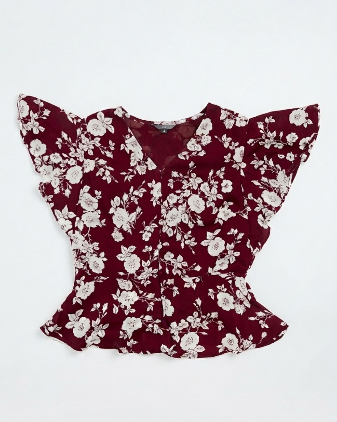 A burgundy floral blouse with dramatic ruffled sleeves and a peplum hem, laid flat against a white background.