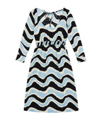 A long-sleeve midi dress with a wavy, zig-zag pattern in black, light blue, and cream, featuring a tie-neck detail and a textured waistband.