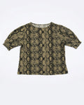 A short-sleeve crop top featuring a black and olive green snakeskin pattern, laid flat against a light gray background.