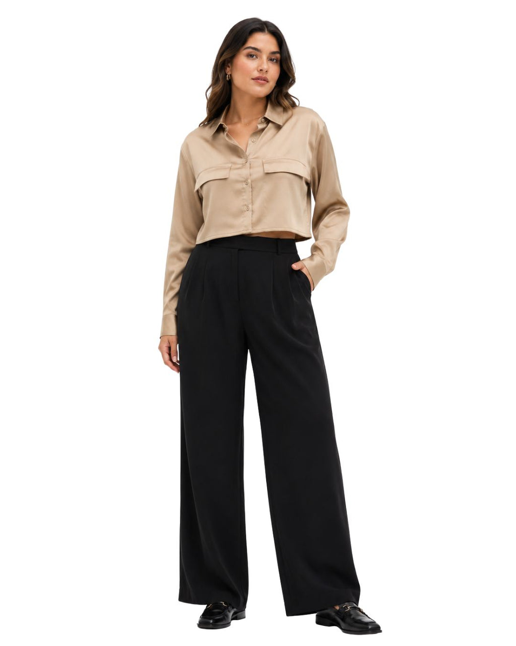 A woman modeling a cropped beige button-up shirt with chest pockets and black wide-leg trousers, standing against a plain white background.