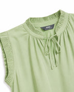A close-up of a light sage green sleeveless top with a ruffled high neckline, tie-front detail, and pleated sleeve edges. A dark gray neck label reads 'max'.