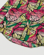A close-up of a colorful butterfly print fabric, featuring vibrant pink, green, yellow, and light blue butterflies outlined in black on a white background.
