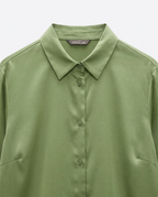 An olive green long-sleeve button-up shirt with a classic pointed collar, shown in a close-up view against a light gray background.