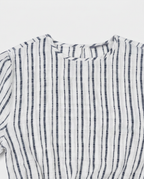 A close-up of a white cotton gauze top with vertical navy blue stripes, showing the textured fabric and collar detail.