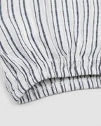Close-up of a striped fabric product, showing vertical navy blue stripes on a white textured material, folded to reveal the weave and hem.