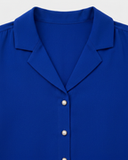 A close-up of a royal blue button-down shirt with a pointed collar and pearl-like buttons.