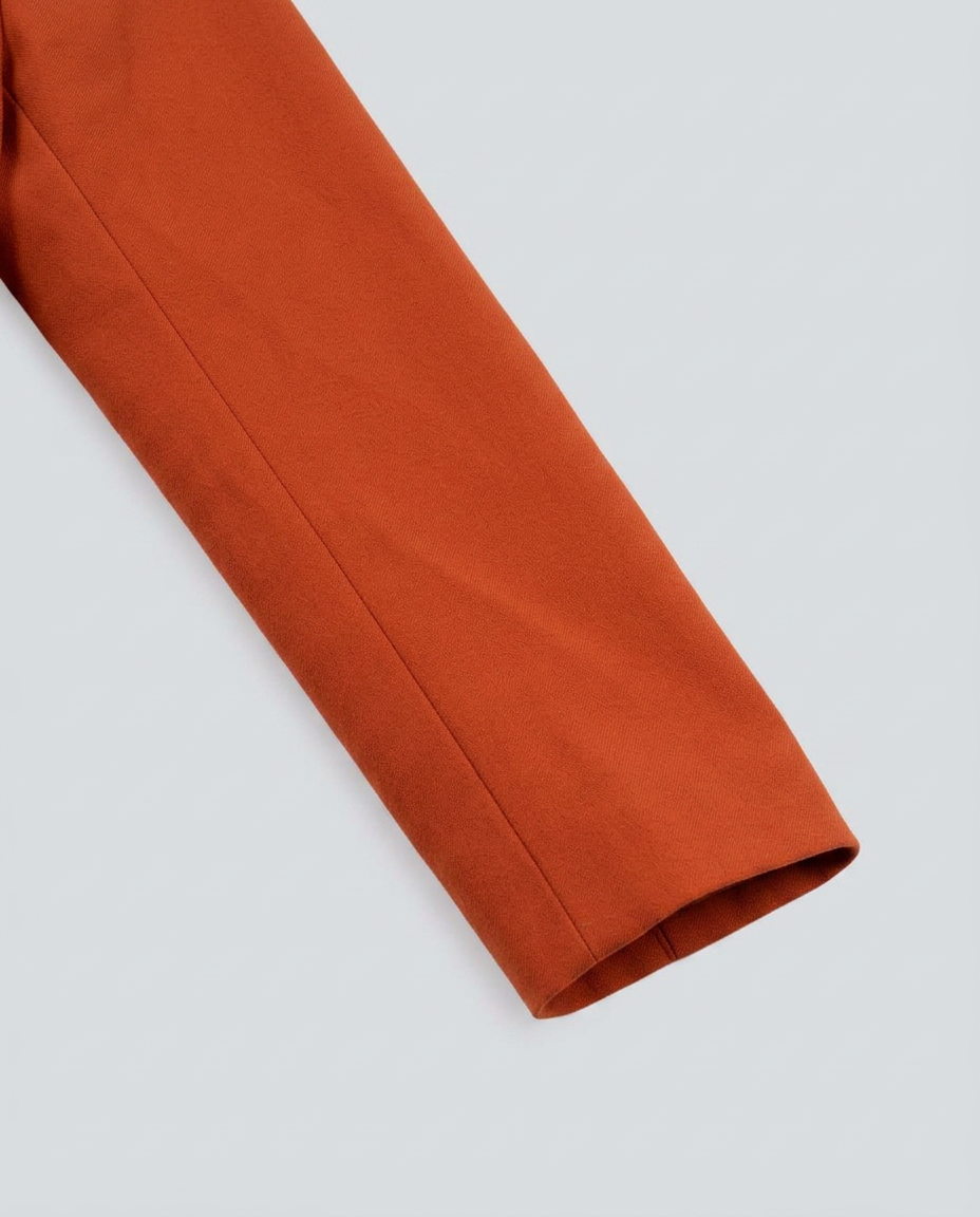 A close-up of a rust-orange fabric sleeve or trim against a light gray background.