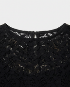 Close-up of a black lace top showing the intricate floral lace pattern and the inner neckline with a small keyhole cutout.